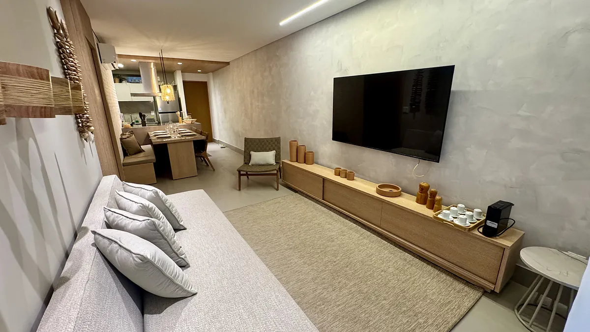 Sala de estar com sofá claro, tapete de fibra e marcenaria em madeira ao longo da parede.
