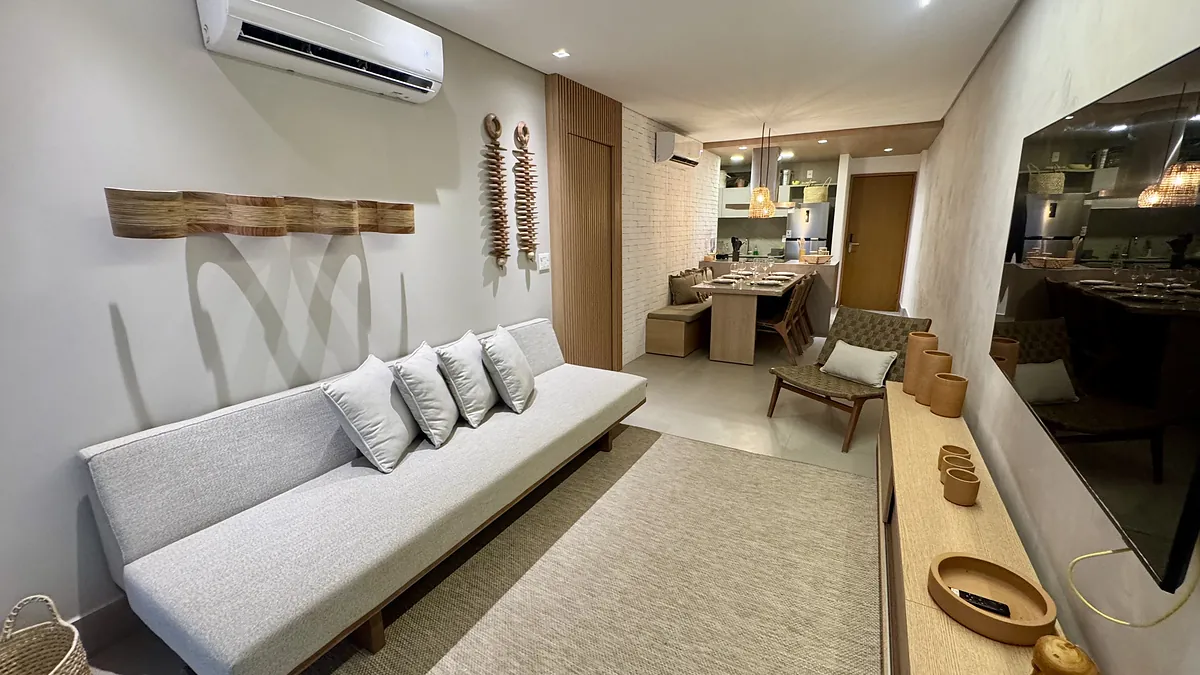 Sala de estar com sofá claro, tapete de fibra e marcenaria em madeira.
